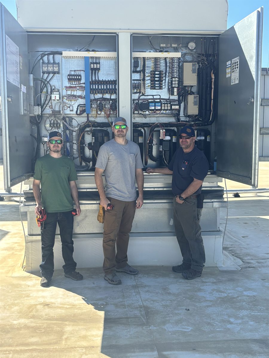 Edwards Electric owners in front of rooftop mechanical and electrical equipment